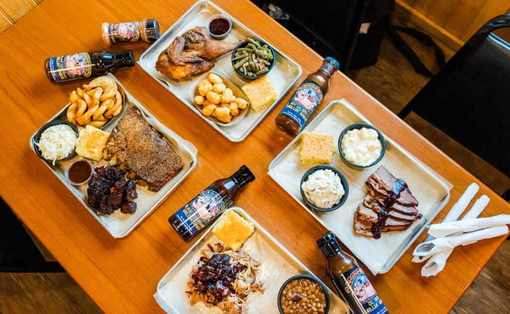 table full of bbq food, brisquets, chicken, ribs, pulled pork, and sides