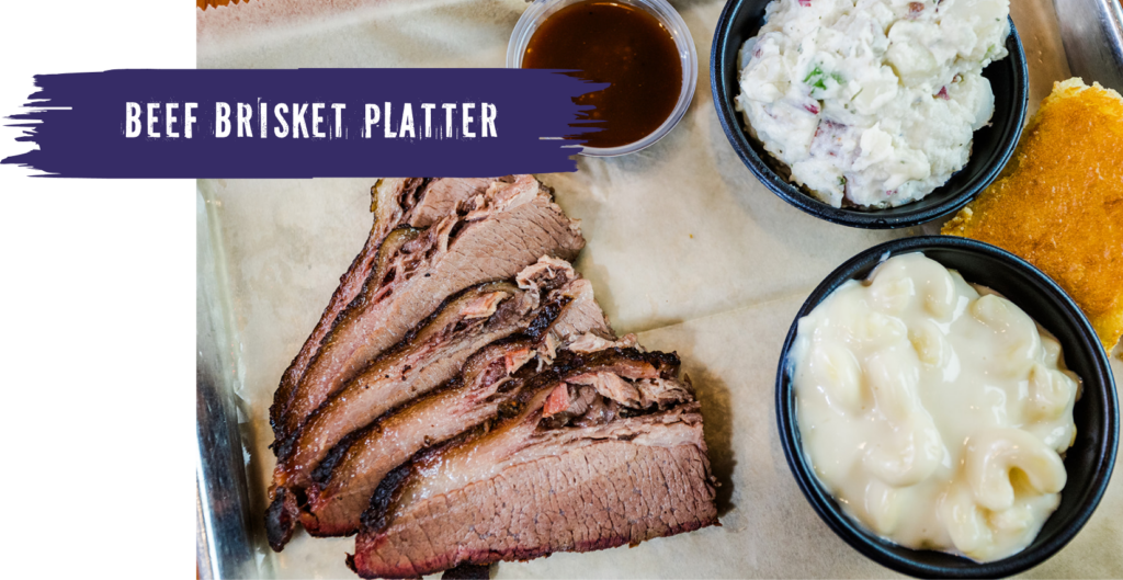 beef brisket platter on a tray with mac and cheese, corn bread, and potato salad